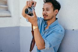 Man taking photo with digital camera holding camera away from his face