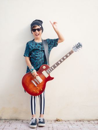 Energetic kid gesturing rock holding guitar