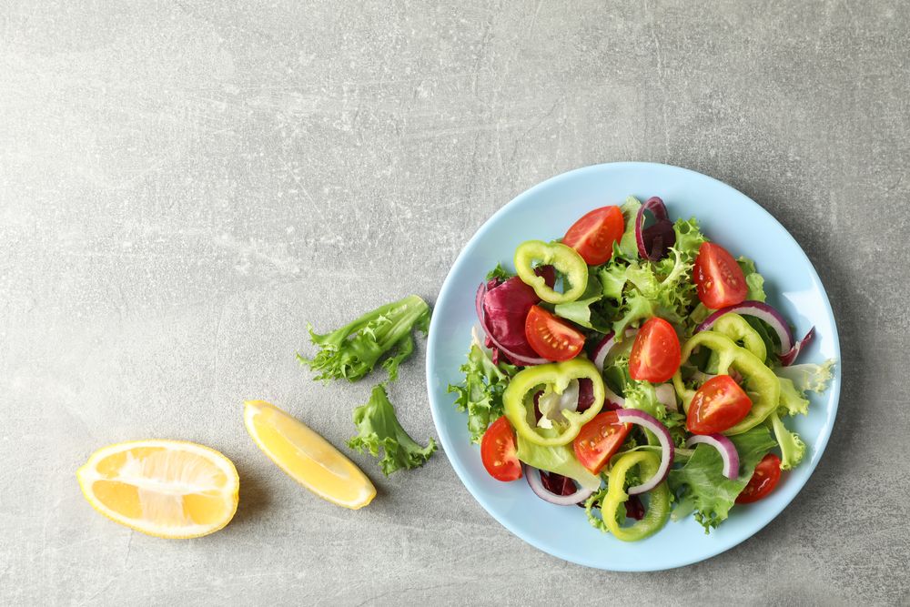 Salad of fresh vegetables on grey background, top view
