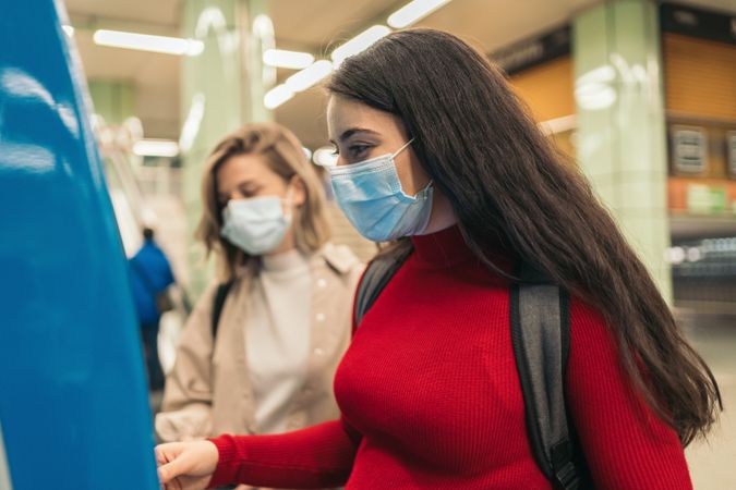 Women buying ticket for metro with mask