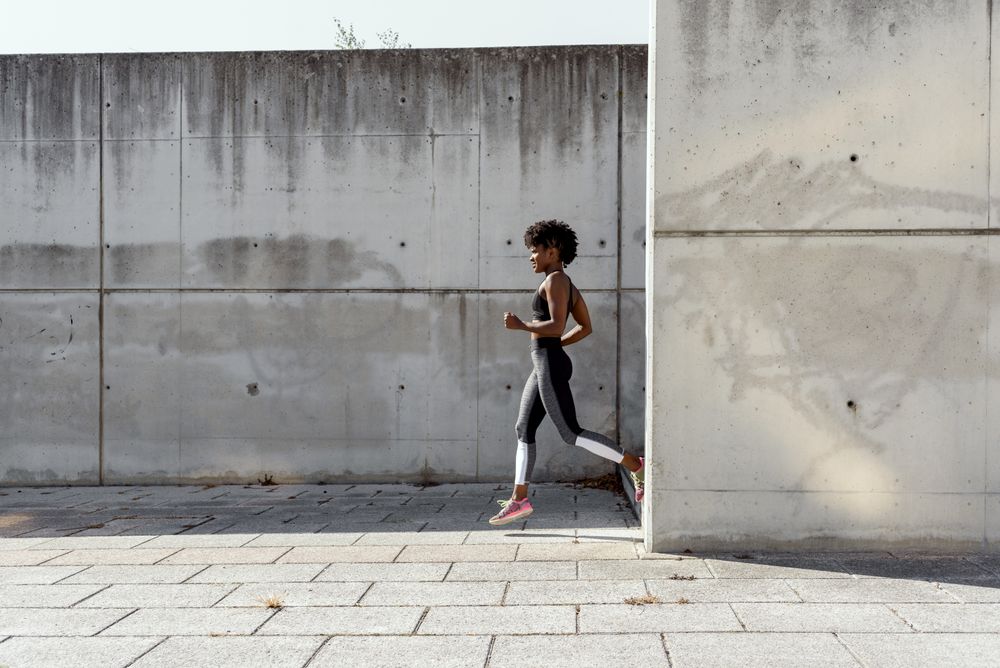 Black sportswoman running down stairs in city