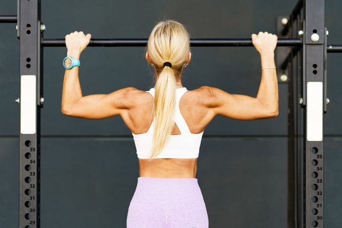 Back of fit woman doing pull ups on bar