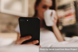 Woman looking at her mobile phone while having coffee 0VWWj5