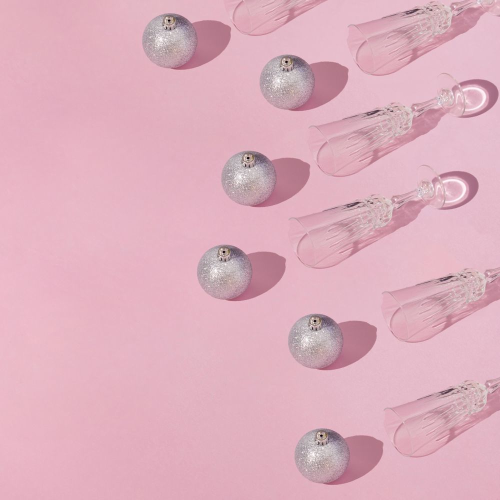 Christmas winter holidays design with decorations and crystal glasses on a pink background