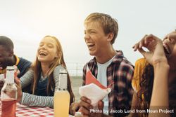 Close up of teenage friends laughing and having fun sitting in a restaurant outside 5R1mr0