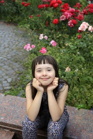 Beautiful girl with bangs sitting near a garden