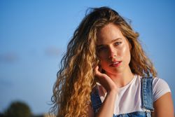 Young woman touching face against blue sky