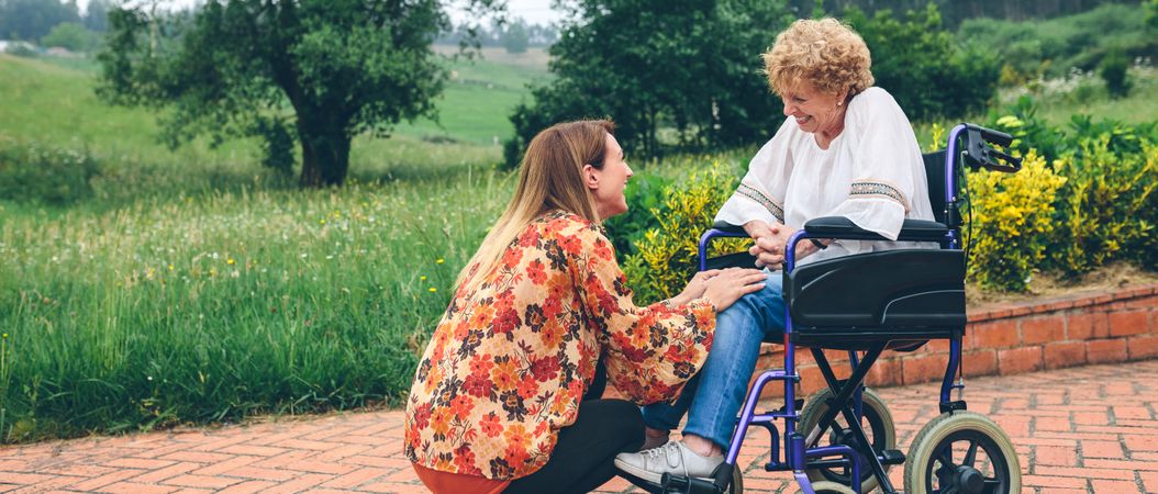 Young woman talking to older woman in a wheelchair