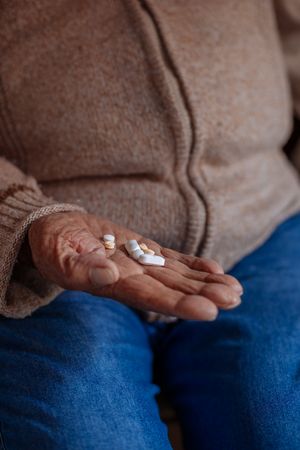 Detail of pills on the hand of an old man