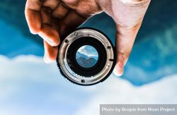 Person holding camera lens showing mountain 48nEv0
