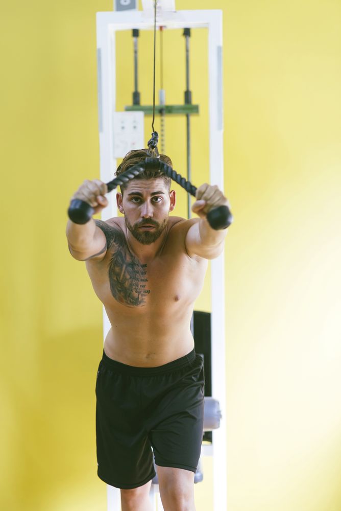 Fit male in gym working out his arms using weights machine
