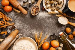 Baking ingredients framing a dark counter with copy space