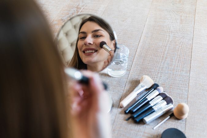 Happy woman applying powder and recording video on camera