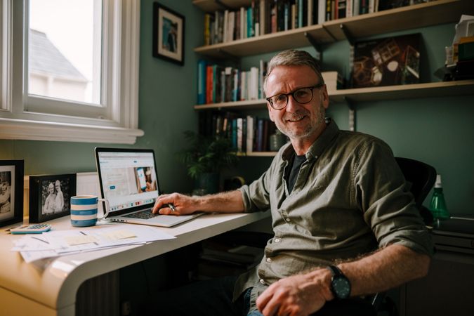 Mature smiling man smiling while working at home office