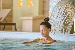 Woman standing under waterfall in pool