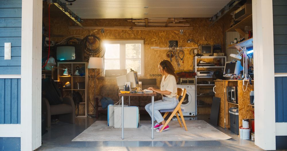 Hispanic Female Software Developer Programming On Old Desktop Computer In Retro Garage With Random Appliances.