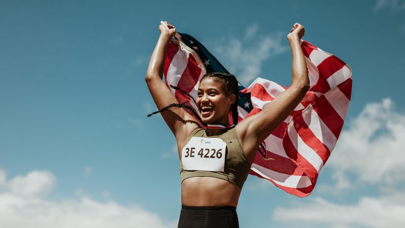 Athlete holding the American flag over the head and smiling