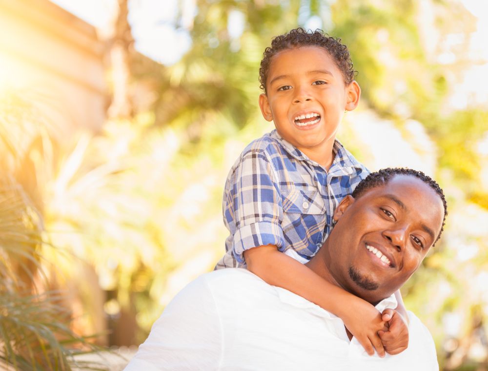 Smiling Son and Father Playing Outdoors Together On Sunny Day