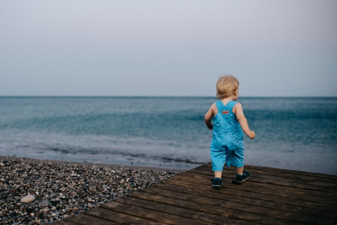 Toddler standing on wooden dock at the beach