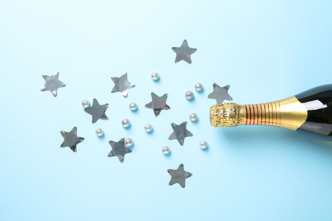 Champagne bottle and glitter on blue background, space for text