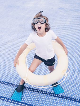 Funny boy with swimming ring and mask in empty pool