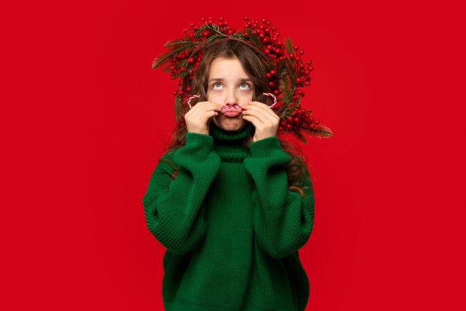 Young girl making playful mustache with candy canes