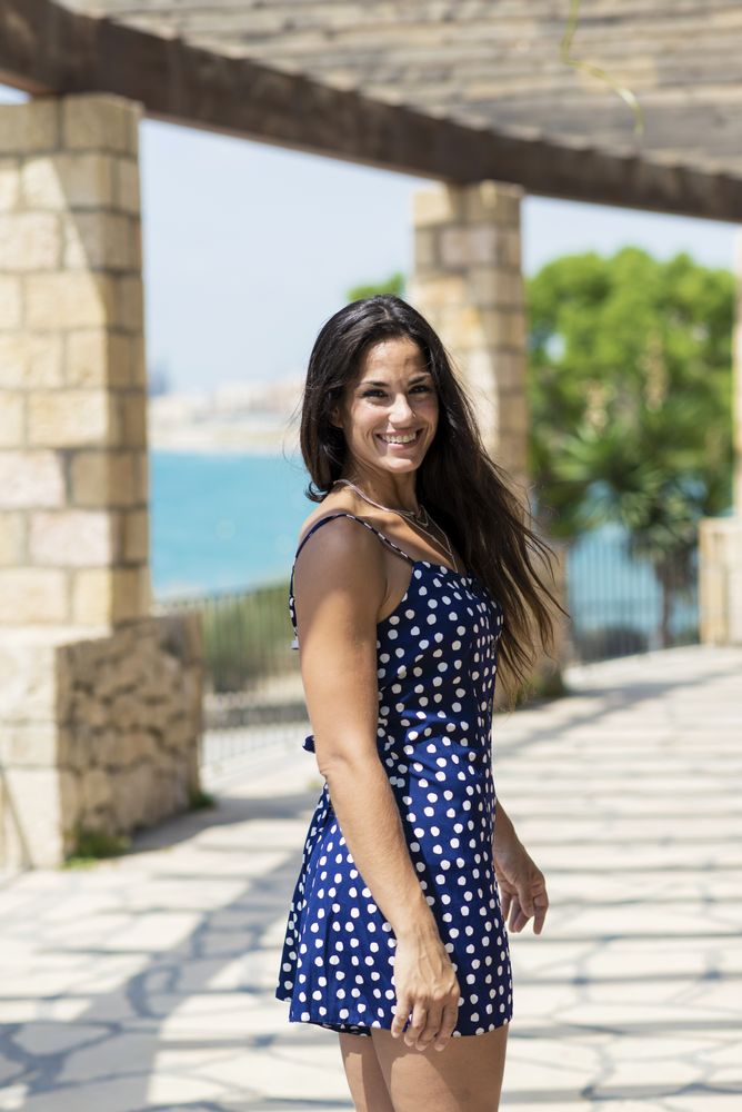 Beautiful hispanic woman in blue dress standing outdoors while looking camera