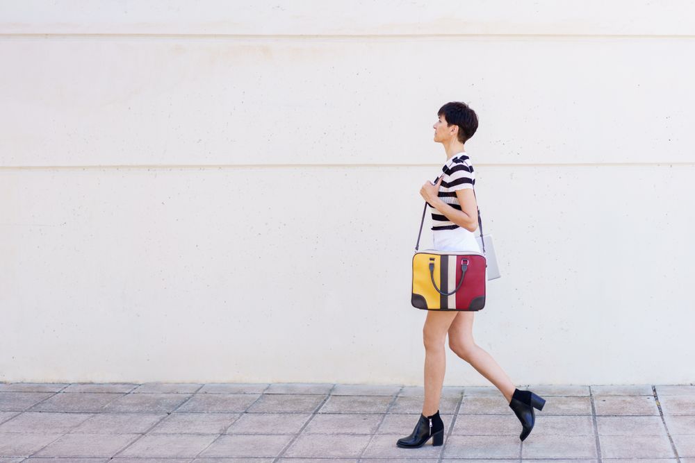 Woman walking down the street with ankle boots and colorful computer bag