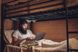 Man using laptop in rustic bunk bed