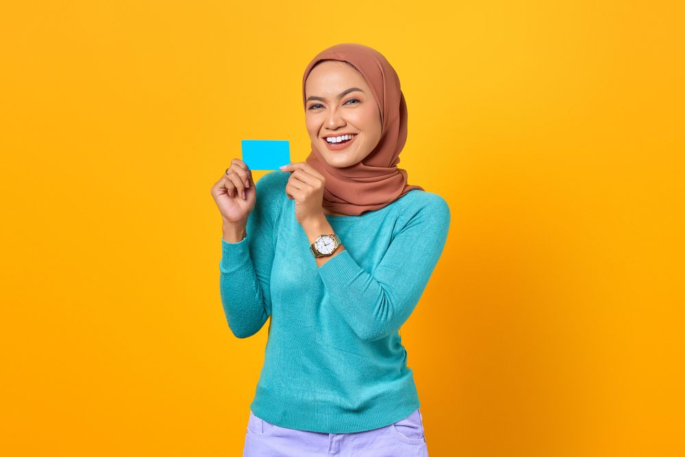 Muslim woman happy and holding credit card with both hands