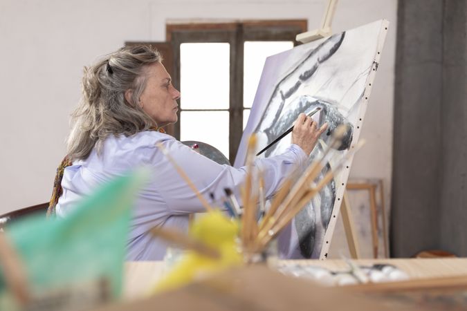 Mature artist woman painting at her workshop