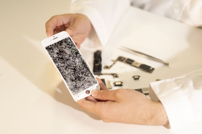 Crop hands showing broken smartphone display