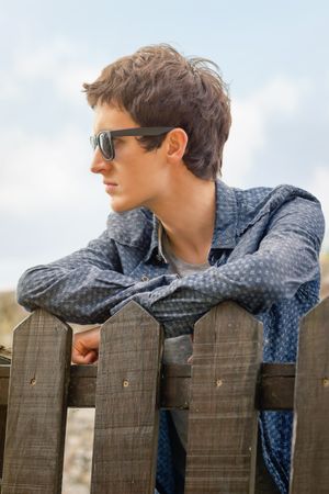 Hipster man with sunglasses over a fence