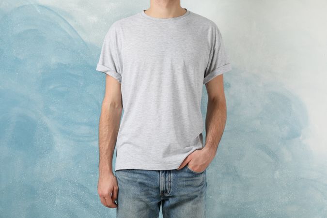 Men in blank grey t-shirt against blue background, space for text