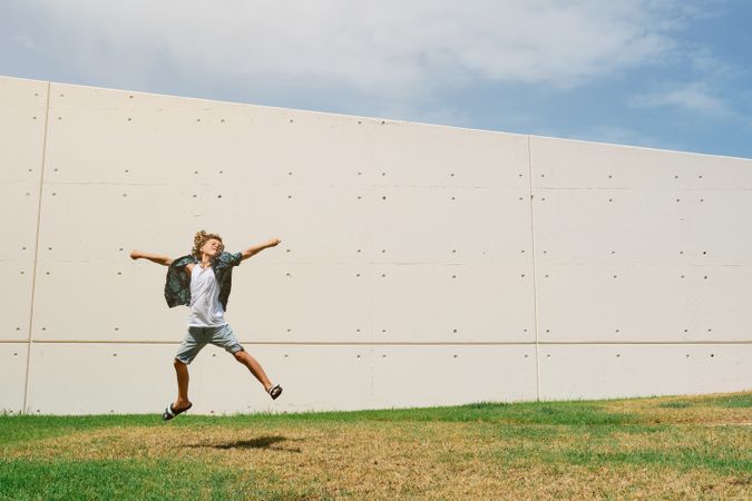 Carefree boy jumping against wall