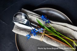 Spring table setting with blue scilla siberica over silverware wrapped in napkin bYqqL6