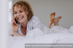 Woman talking on mobile phone lying on bed 0KMm3A