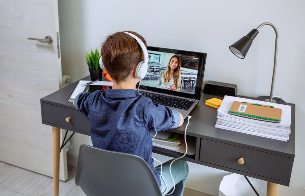 Unrecognizable boy with headphones receiving class at home with laptop from his bedroom