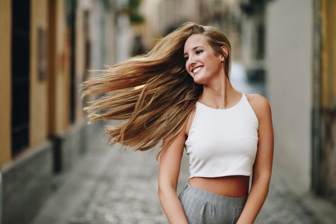 Long haired chic woman smiling outside with hair flicking in the wind