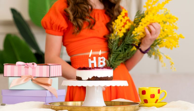 Girl smiling behind birthday cake with "HB" candles