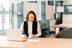 Woman in dark blazer sitting at the table using laptop
