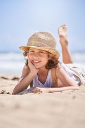 Cheerful boy leaning on hand while relaxing on seashore