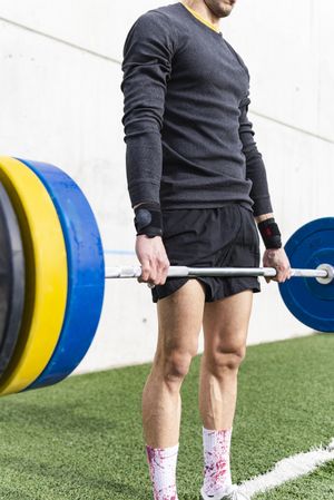 Man training with barbell on sports ground