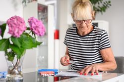 Mature woman preparing pill box at home
