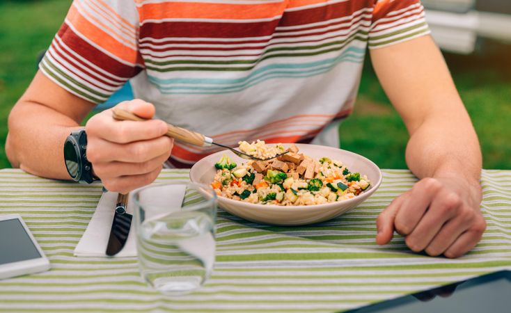 White male eating vegetable dish on outdoor table