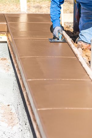 Construction Worker Using Stainless Steel Edger On Wet Cement Forming Coping Around New Pool