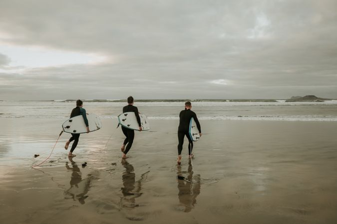 People with surfboard walking near sea