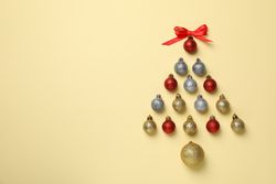 Christmas tree made of baubles on beige background, space for text