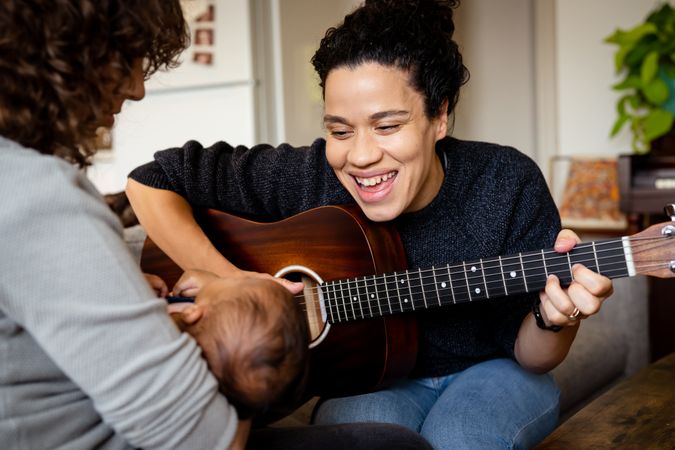 Woman playing songs with guitar for baby and partner