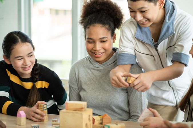 Three happy students working with blocks on table